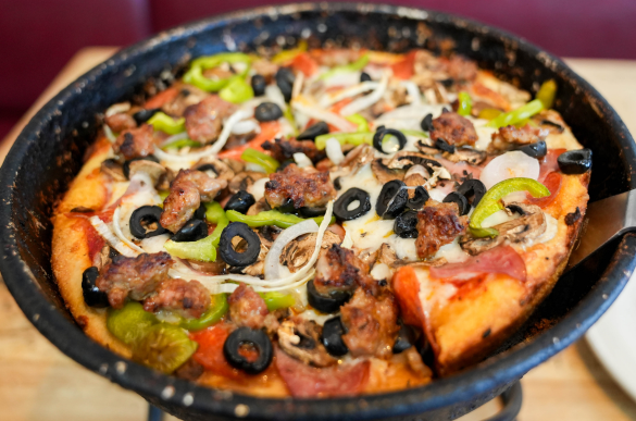 a pizza with olives and peppers in a pan