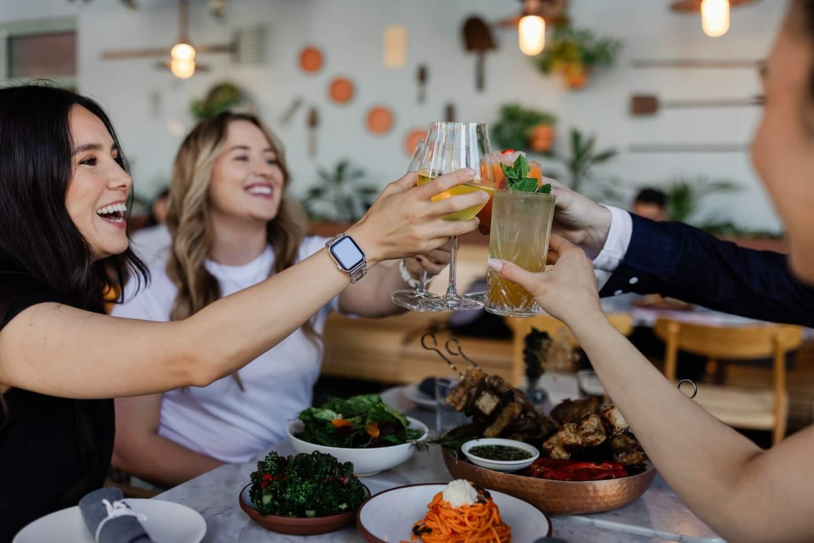 Friends cheering with cocktails at Eataly, one of the best things to do in Santa Clara.